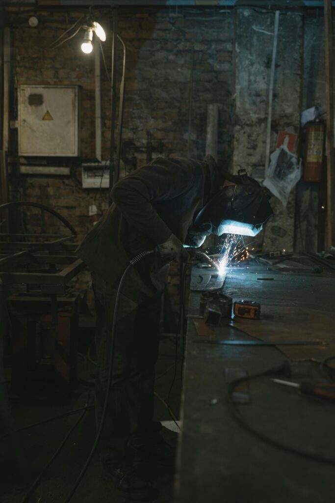 pexels photo 5846274 5846274 A blacksmith welding in a dimly lit workshop, focused on metal forging processes.